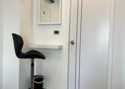 Small workspace with a high chair and a wall-mounted desk next to a door