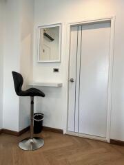 Small workspace with a high chair and a wall-mounted desk next to a door