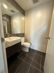 Modern bathroom with sink, toilet, and large mirror