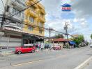 Street view with a building and a small red car