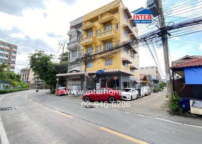 Street view of a yellow multi-story building with signage.