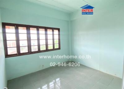 Empty bedroom with large window, light blue walls, and tiled floor.