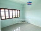 Empty bedroom with large window, light blue walls, and tiled floor.