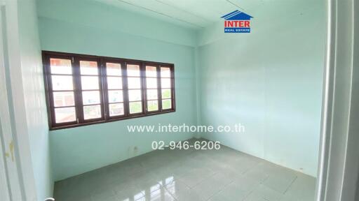Empty bedroom with large window, light blue walls, and tiled floor.