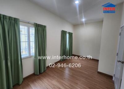 Unfurnished room with wooden floor and large windows with green curtains