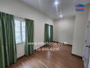 Unfurnished room with wooden floor and large windows with green curtains