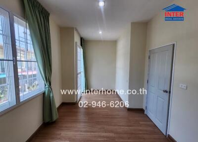 Empty room with wooden floor, green curtains, and a closed door
