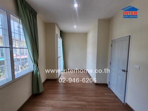 Empty room with wooden floor, green curtains, and a closed door