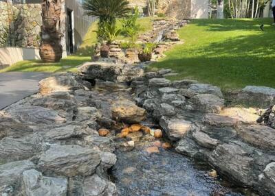 Lush garden with rock stream and palm trees