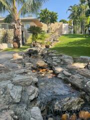 Lush garden with rock stream and palm trees