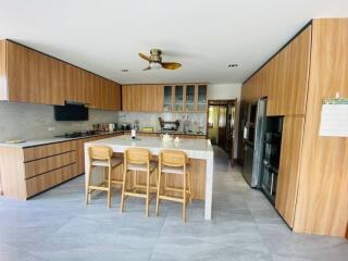 Modern kitchen with island, wooden cabinetry, and bar stools