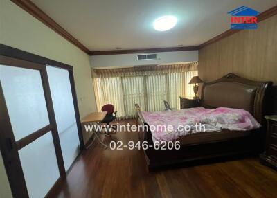 Spacious bedroom with bed, desk, and wooden flooring