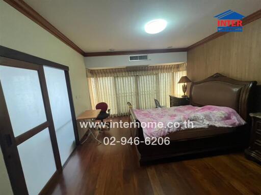 Spacious bedroom with bed, desk, and wooden flooring