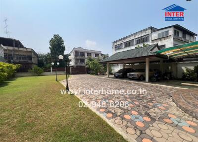 Outdoor area with pathway, greenery, and covered parking spaces