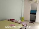 Simple bedroom with single bed, neutral wall colors, air conditioner, and a small green stool.