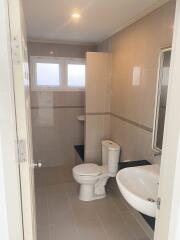 A well-lit bathroom with toilet, sink, and a partial view of the shower.