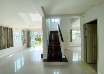 Spacious living area with open floor plan, staircase, and large windows