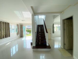 Spacious living area with open floor plan, staircase, and large windows