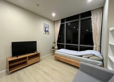 Living room with a TV, single bed, and large window