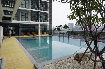 Outdoor swimming pool area with lounge chairs and nearby buildings