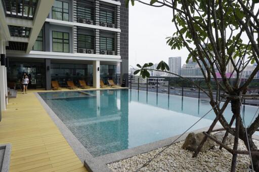 Outdoor swimming pool area with lounge chairs and nearby buildings