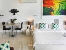 Modern studio apartment featuring a bed, dining area, and colorful wall art