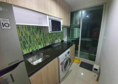 Modern kitchen with green tiled backsplash, appliances, and washing machine