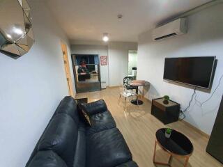 Modern living room with black couch, TV, and dining area