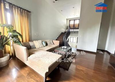 Modern living room area with a sectional sofa, decorative pillows, potted plant, and staircase leading to upper level