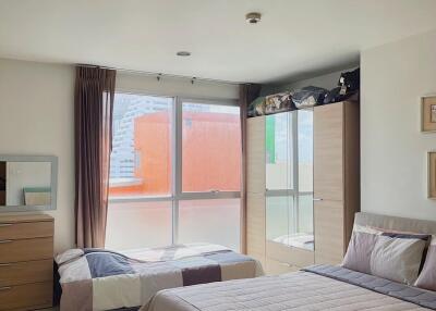 Spacious bedroom with a double bed, single bed, wardrobe, and a window with city view