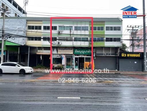 Front view of a commercial building with multiple floors and a sign indicating a real estate company