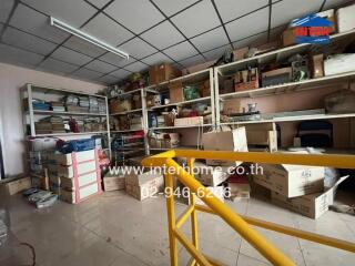 An indoor storage room with various items on shelves and boxes on the floor