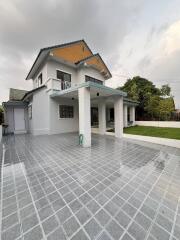 Exterior view of a two-story house with a large driveway and a lawn