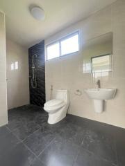 Modern bathroom with shower, toilet, sink, and large mirror