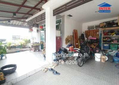 An outdoor space with a partially covered patio and various items stored.