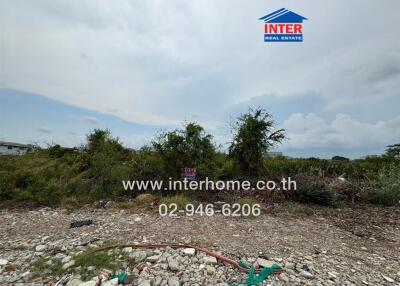 Vacant land with visible signage and overgrown vegetation