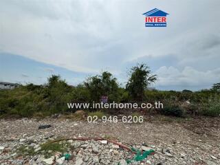 Vacant land with visible signage and overgrown vegetation