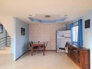 Dining area with wooden dining table, chairs, a cabinet, and fridge