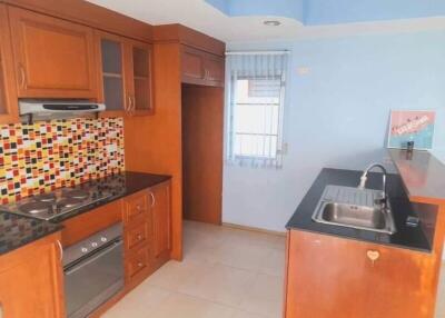 A modern kitchen with wooden cabinets, a tiled backsplash, and a window.