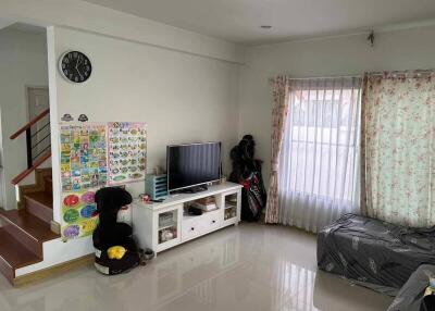 Living room with TV, decorations, sofa, and staircase