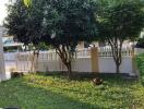 Well-maintained garden with trees and a white fence