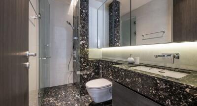 Modern bathroom with glass shower, marble countertop, and wall-mounted fixtures