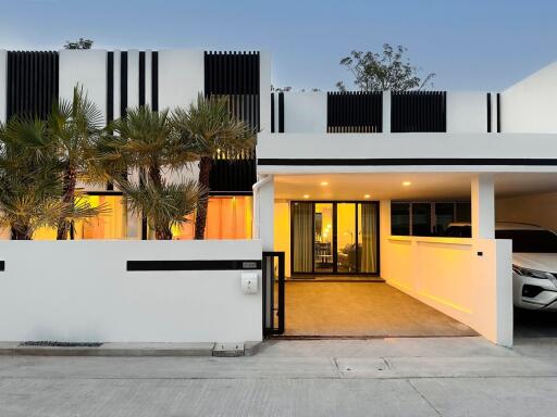 Modern white house exterior with carport and palm trees