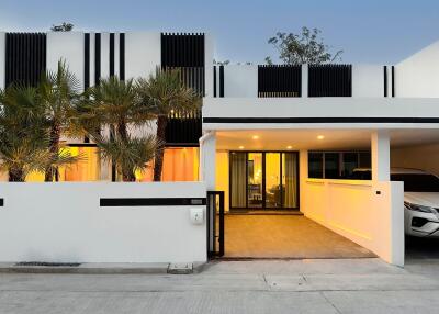 Modern facade of a white house with a carport and palm trees