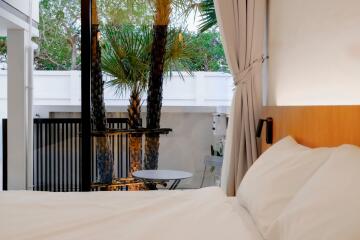 Cozy bedroom with a view of an outdoor patio and palm trees.