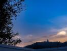 View from a property balcony featuring a scenic landscape with a mountain and a statue at sunset