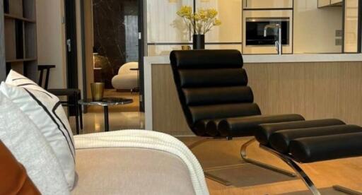 Modern living area with lounge chair, a view into stylish kitchen