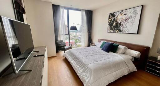 Modern bedroom with a large bed, wall art, TV, and a window view