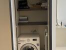 Compact laundry area with washing machine and storage shelves