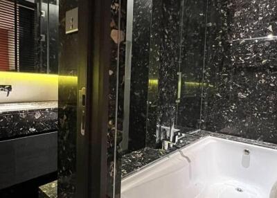 Modern bathroom with dark marble design, bathtub, and vanity